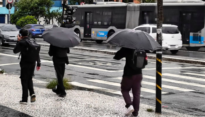 Pedestres se protegem da chuva nas ruas do Jardim Consórcio, na zona sul da cidade de São Paulo...